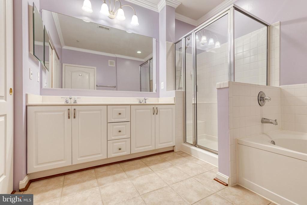 Bathroom with a double-sink vanity, glass shower, and built-in bathtub.
