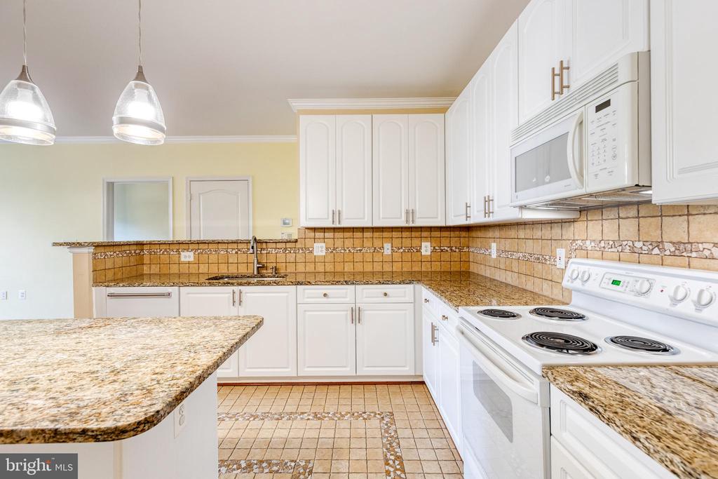 Kitchen with white cabinets, granite counters, tan tile backsplash, and white electric range.