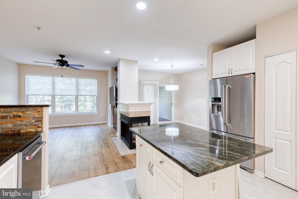 Kitchen with a large granite island, stainless steel appliances, and a stone-faced fireplace.
