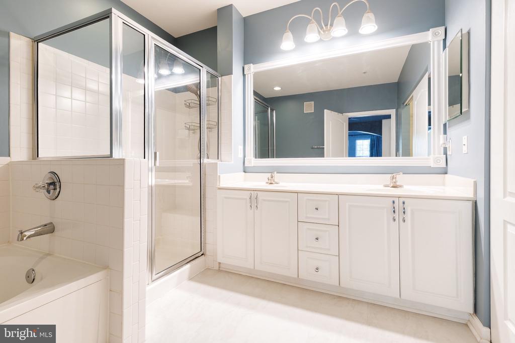Bathroom with a glass-enclosed tub and shower, double-sink vanity, and pale blue walls.