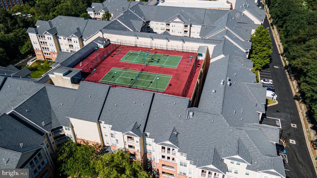 Aerial view of residential buildings surrounding two tennis courts.