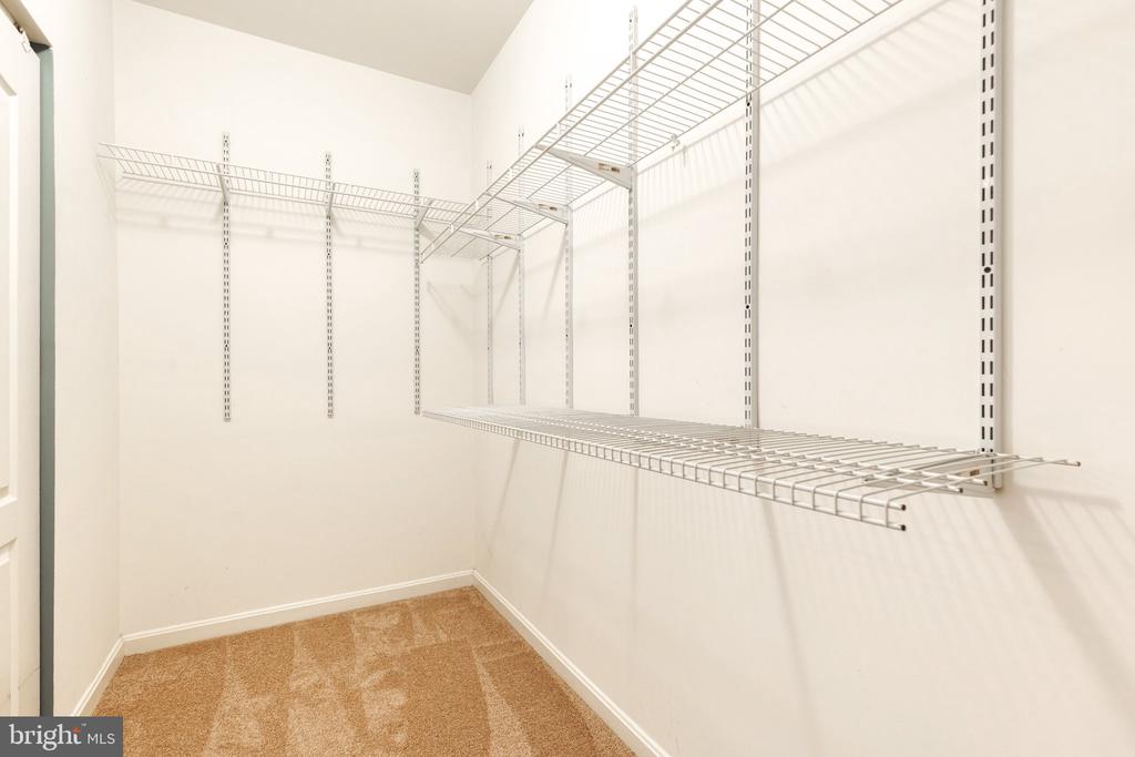 Walk-in closet with extensive white wire shelving and tan carpet.