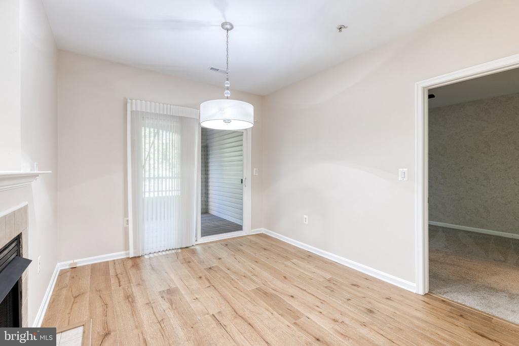 Empty dining room with light hardwood floors, a drum pendant light, and a sliding glass door.