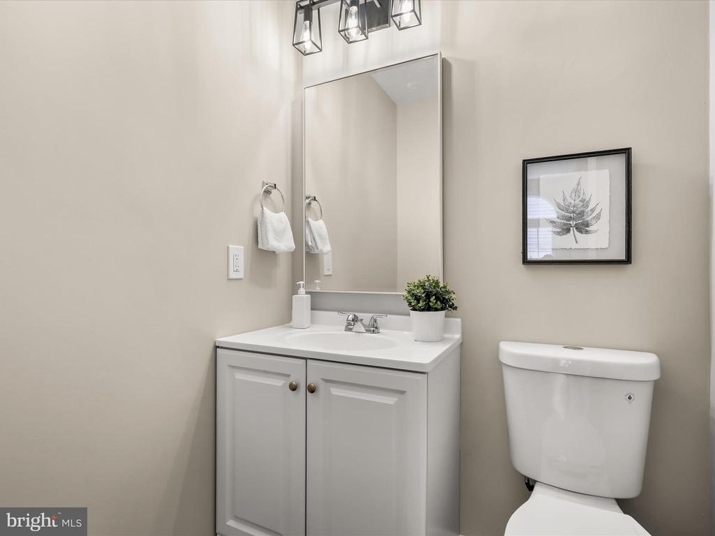 Bathroom with a white vanity, large mirror, toilet, and framed botanical print.