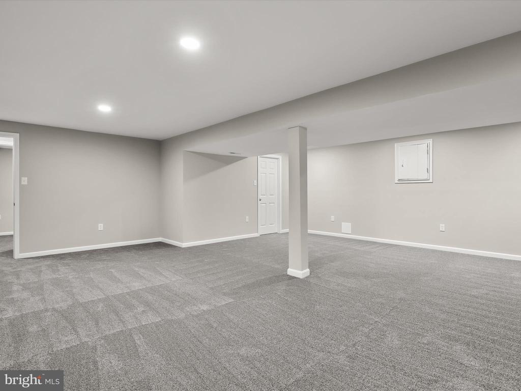 Vacant carpeted basement with recessed lights and a central support column.