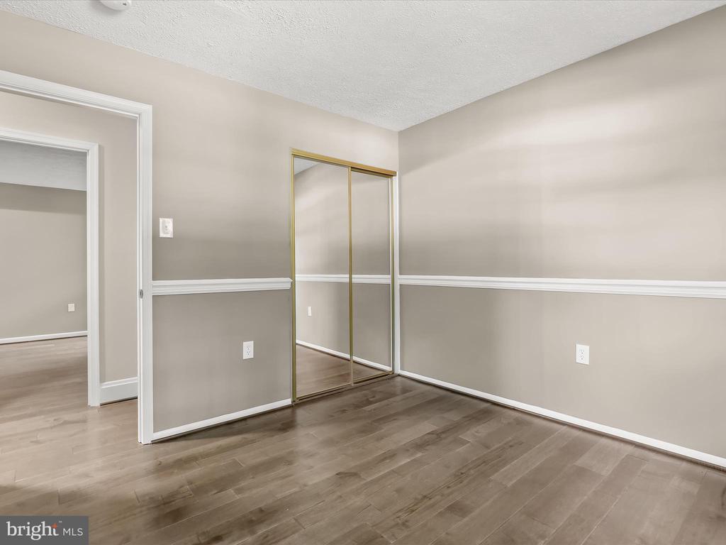 Vacant bedroom with mirrored sliding closet doors and wood-look flooring.