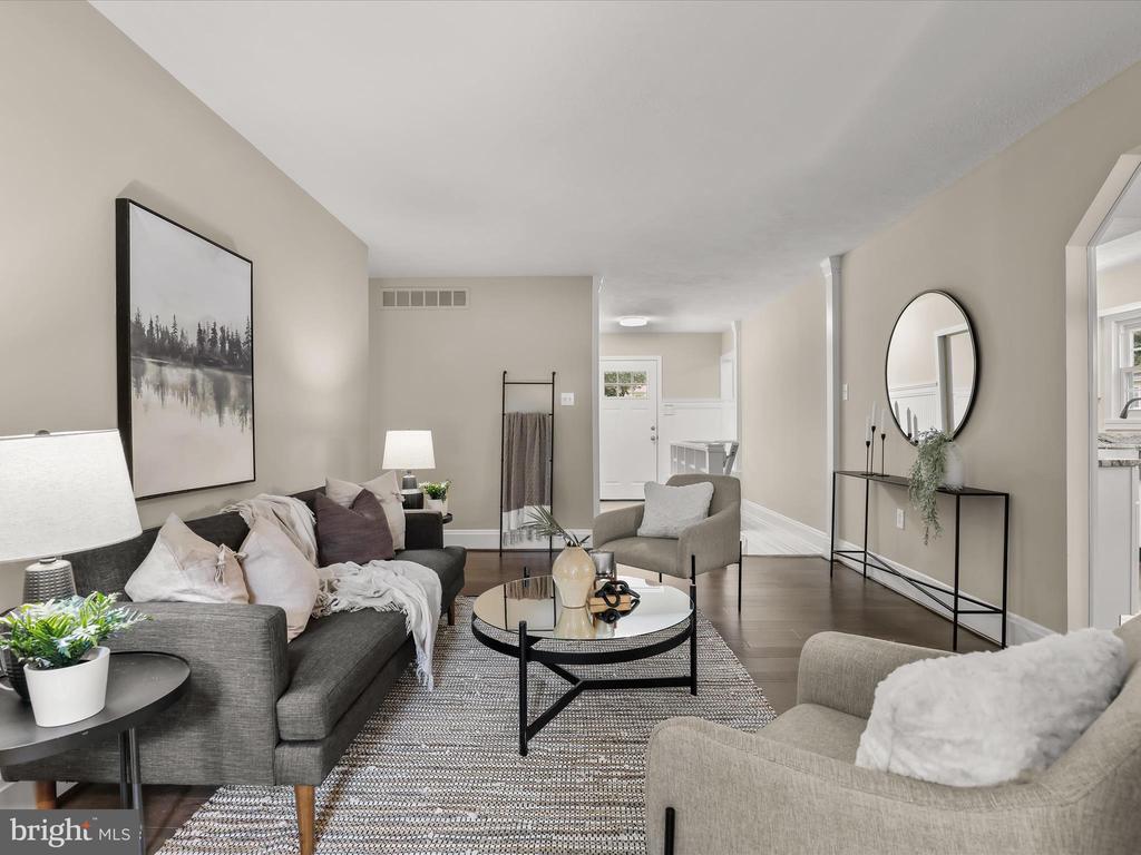 Staged living room with gray seating, a round coffee table, and a console beneath a circular mirror.