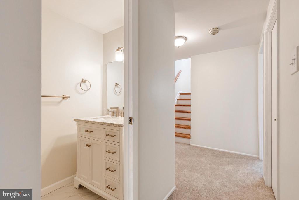 Bathroom vanity beside a carpeted hallway and staircase.