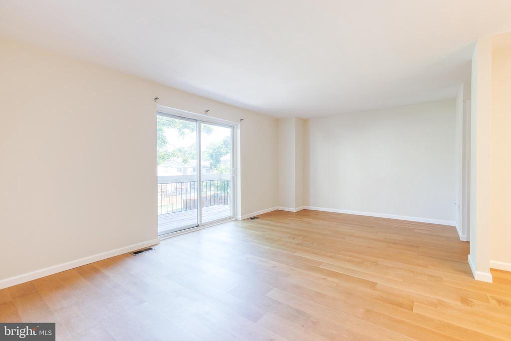Empty living room with light wood floors and sliding glass doors to a balcony.