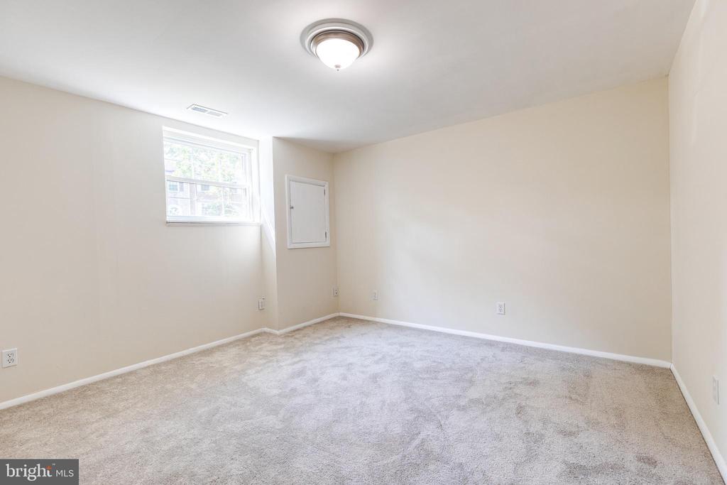 Empty carpeted room with cream walls, a small high-set window, and ceiling light.