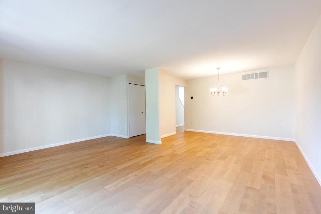 Vacant living and dining area with light wood floors and a chandelier.