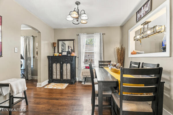 Dining room with a dark wood table, hardwood floors, black cabinet, and chandelier.