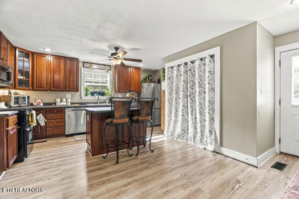 Kitchen with dark wood cabinets, stainless appliances, an island with stools, and patterned curtains.