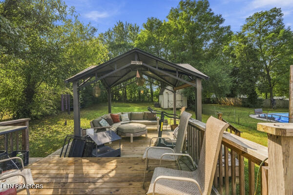 Covered gazebo and furnished wooden deck overlooking a leafy backyard and swimming pool.