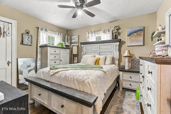 Bedroom with a large bed, white dressers, patterned curtains, and a ceiling fan.
