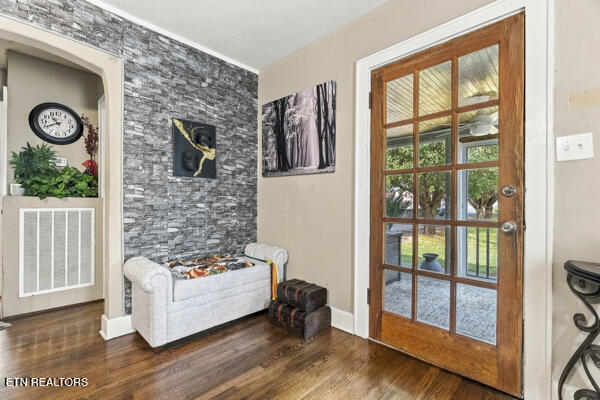 Sitting area with a gray loveseat, stacked-stone accent wall, and wood-framed glass door.
