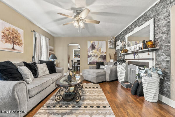 Living room with gray sofas, patterned rug, hardwood floors, and a stone fireplace wall.