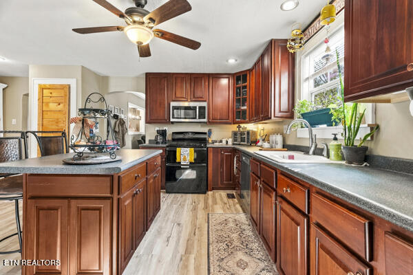 Kitchen with reddish-brown cabinets, a central island, and a sink beneath a window.