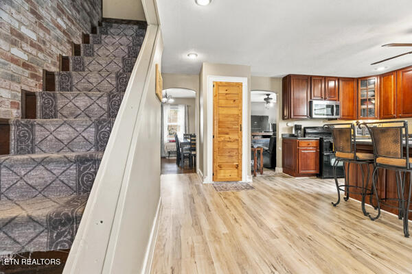 Open kitchen with dark wood cabinets and breakfast bar beside a carpeted staircase.