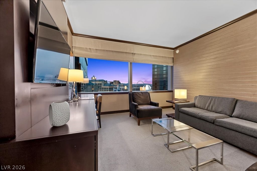 Furnished living room with gray seating and a city skyline visible through large windows.