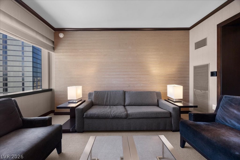 Living room with a gray sofa, dark armchairs and a large window overlooking a glass high-rise.