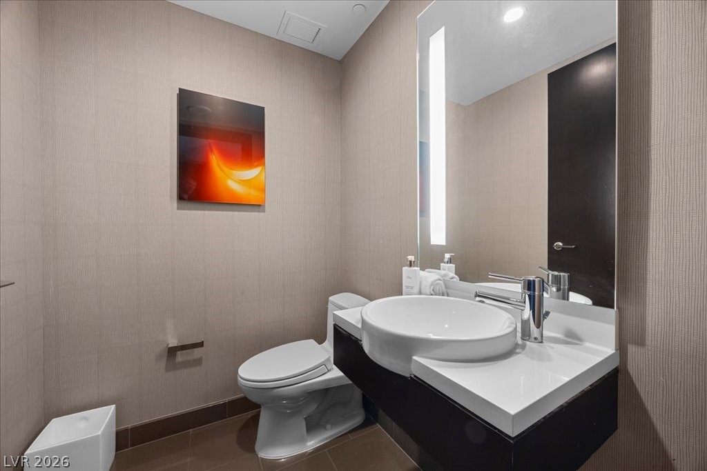 Modern bathroom with a vessel sink, dark vanity, large mirror, and colorful abstract wall art.