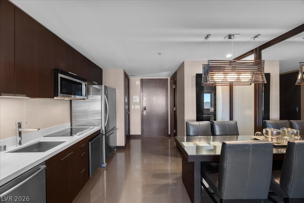 Modern condo kitchen with stainless steel appliances beside a glass dining table and leather chairs.