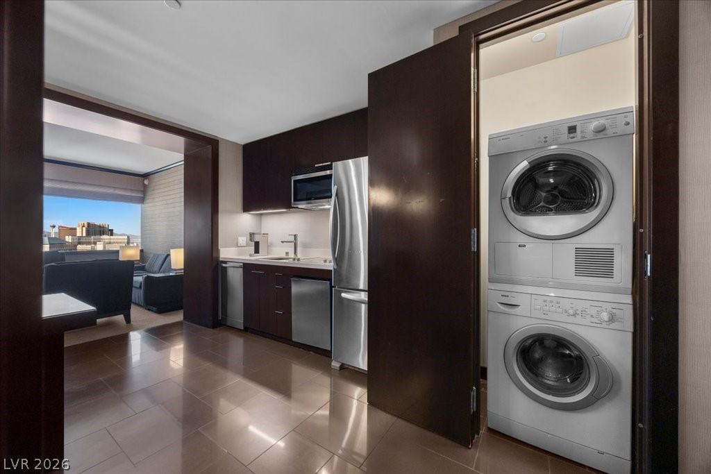 Condo kitchen with dark cabinets, stainless appliances, and a stacked washer and dryer.