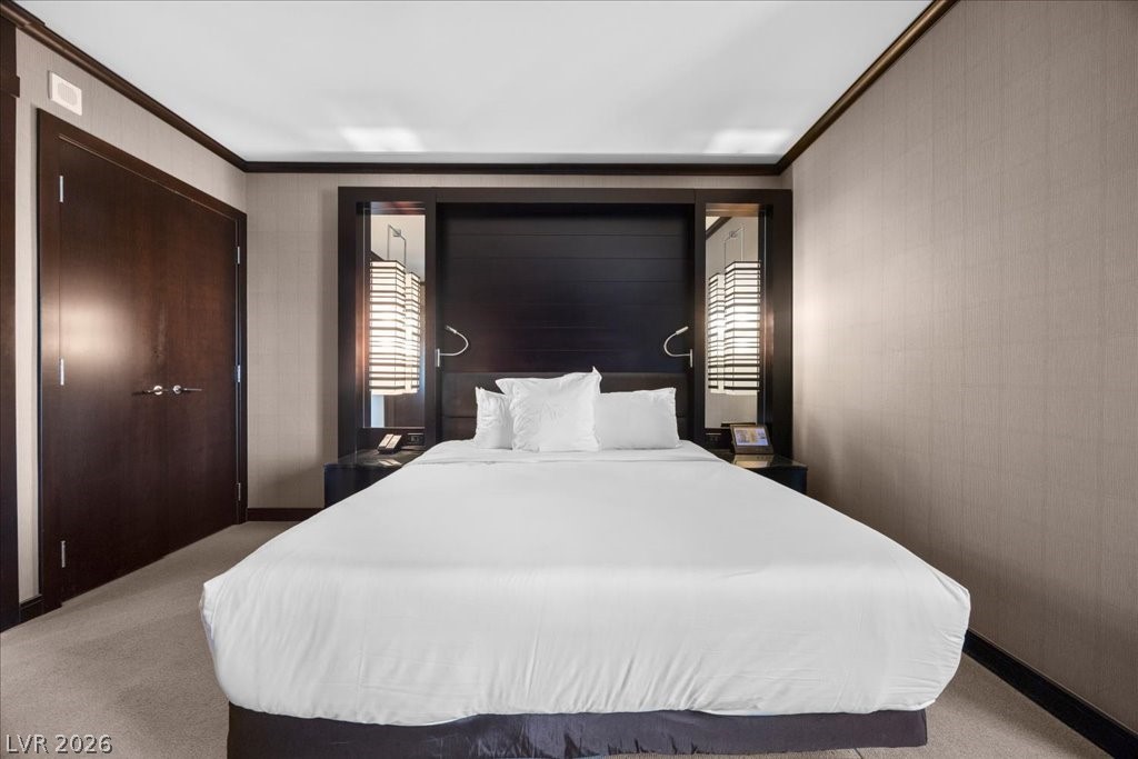 Bedroom with a large white bed, dark wood headboard, and matching bedside lamps.