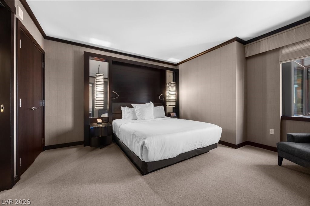 Bedroom with a king-size bed, dark wood headboard, neutral walls, and beige carpet.