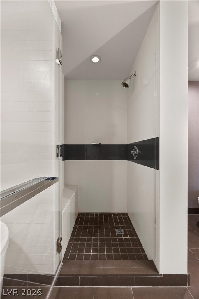 Walk-in shower with a built-in bench, glass doors, and dark tile accents.