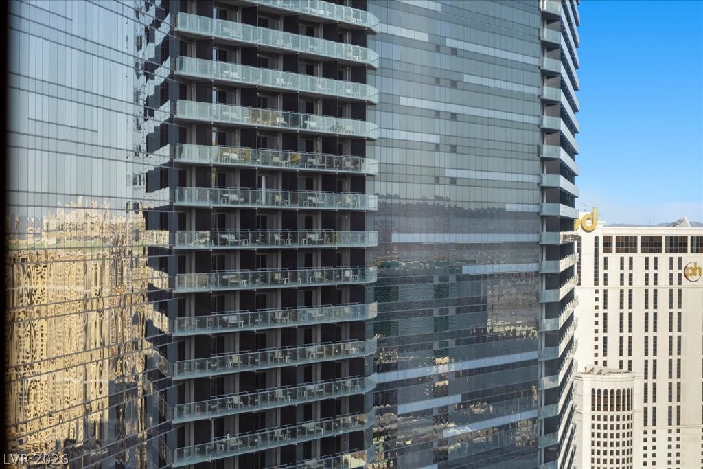 Modern glass high-rise with rows of balconies and neighboring buildings.