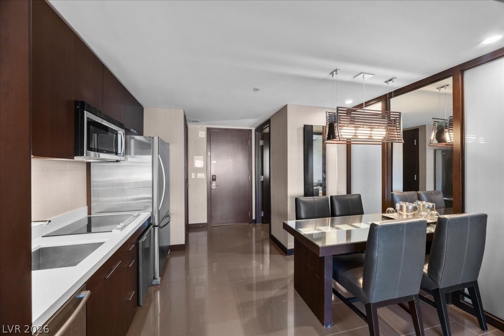 Kitchen and dining area with dark wood cabinets, stainless appliances, and a mirrored wall.