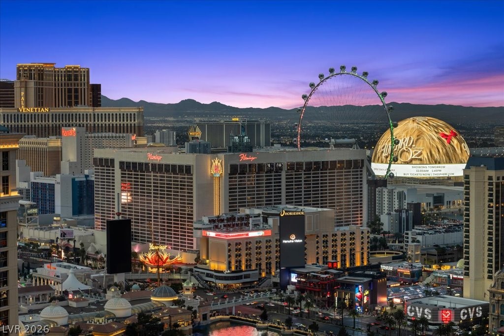 Las Vegas Strip at dusk, with the High Roller wheel, casino hotels, and mountains in the distance.
