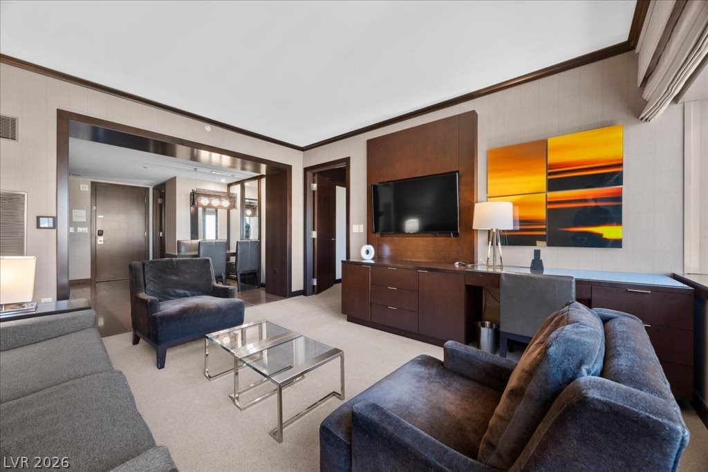 Living room with gray seating, glass coffee tables, and colorful artwork beside the television.