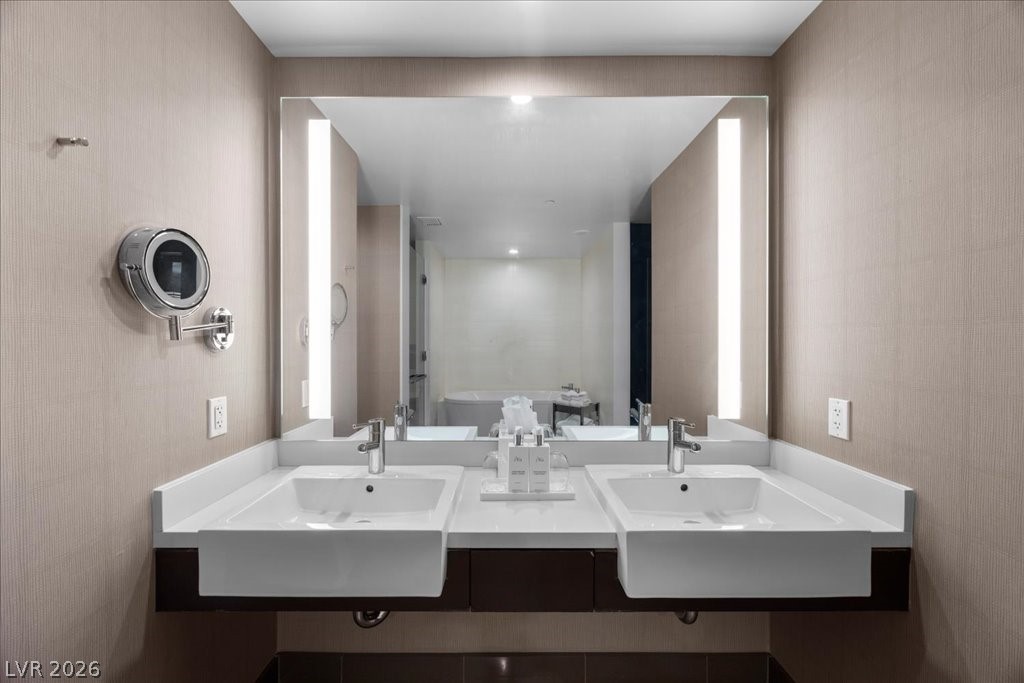 Bathroom with a double-sink vanity, wide mirror, and illuminated vertical panels.