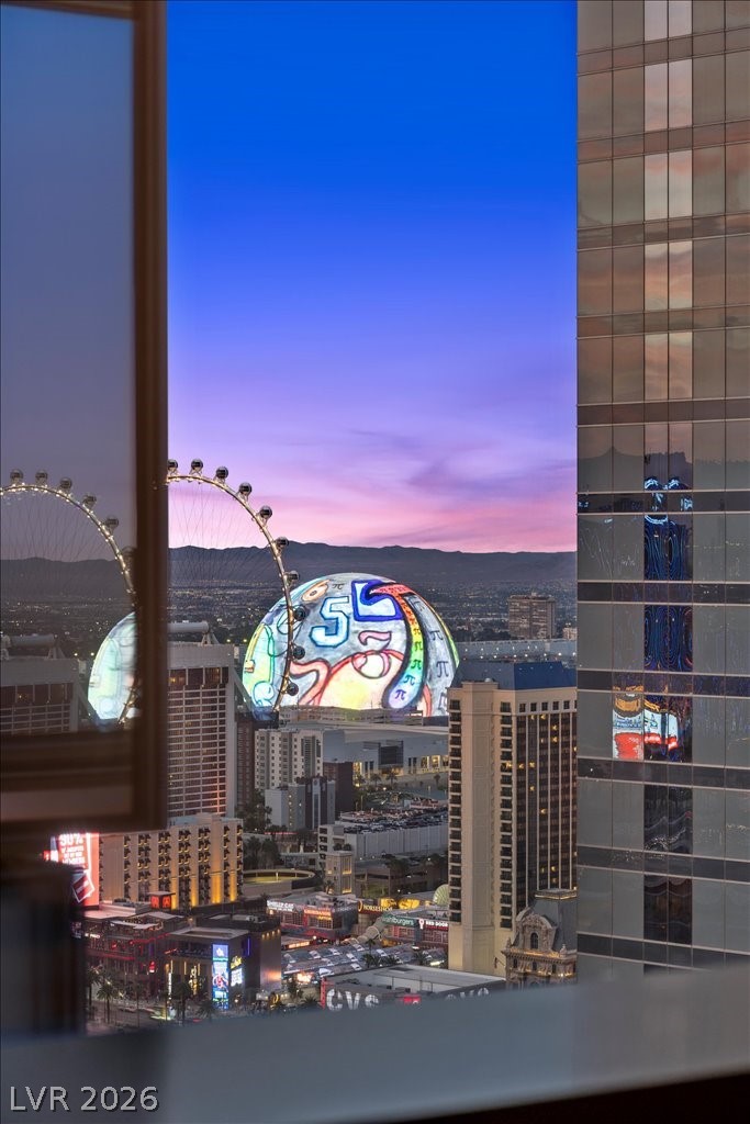 Las Vegas skyline at dusk, with the illuminated Sphere and High Roller framed by a high-rise window.
