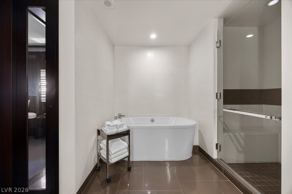 Modern bathroom with a freestanding tub, glass shower, and towel cart.