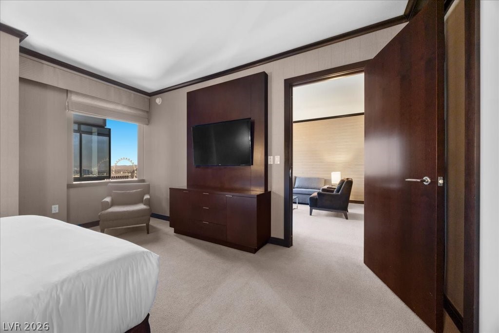Furnished bedroom with dark wood TV cabinetry, an open doorway to a sitting area, and a Ferris wheel view.