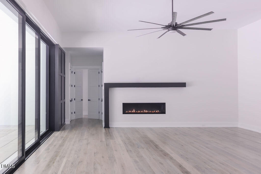 Empty living room with a modern fireplace, ceiling fan, and large sliding glass doors.