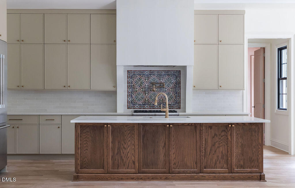 Kitchen with a dark wood island and colorful patterned tile behind the faucet.