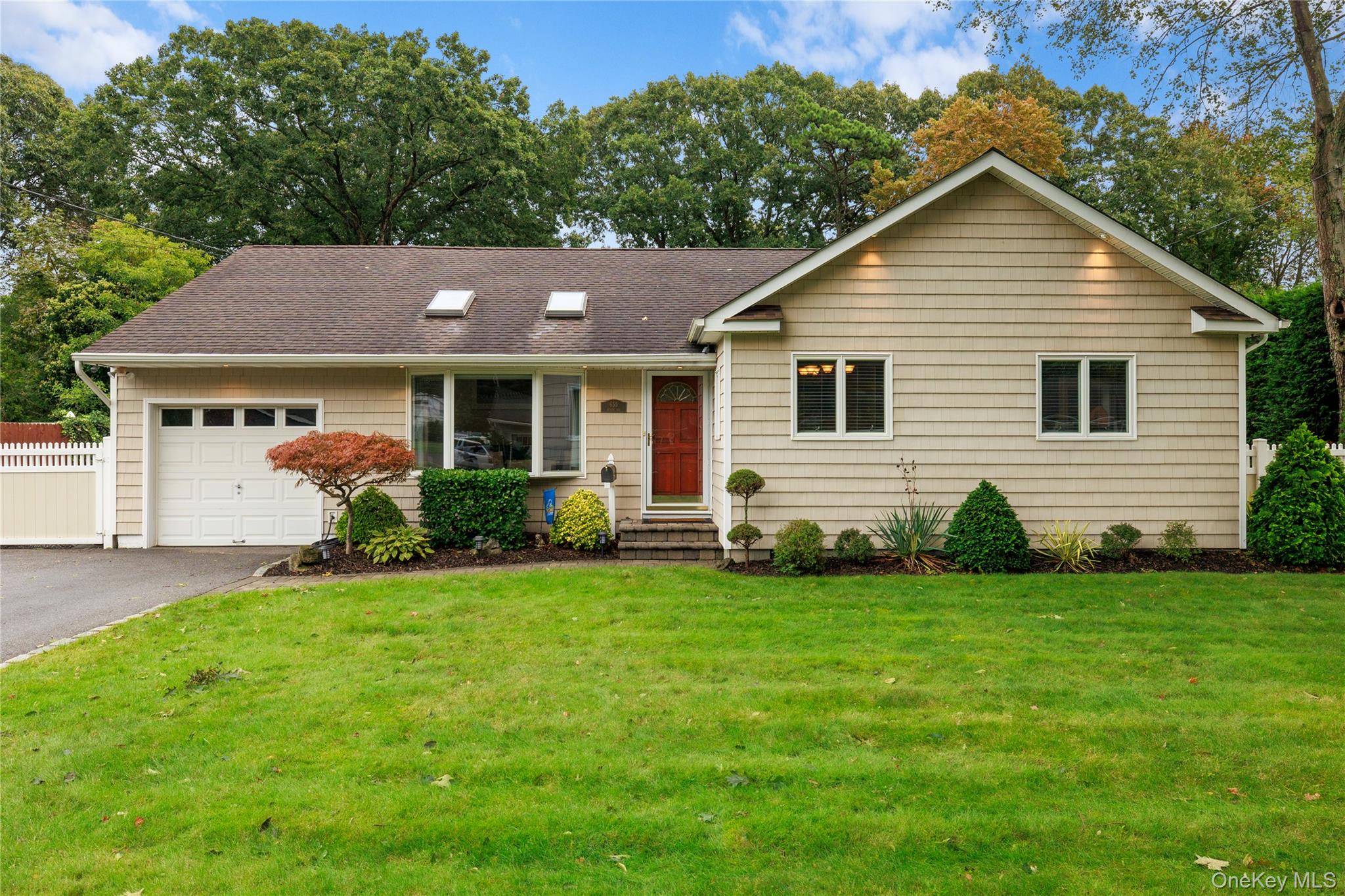 Beige single-story home with a red front door, attached garage, and landscaped lawn.