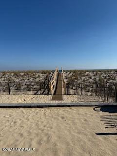 Sandy rooftop terrace with black railings and a raised walkway overlooking a coastal neighborhood.