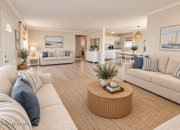 Staged coastal living room with two sofas, woven rug, round coffee table, and open kitchen.