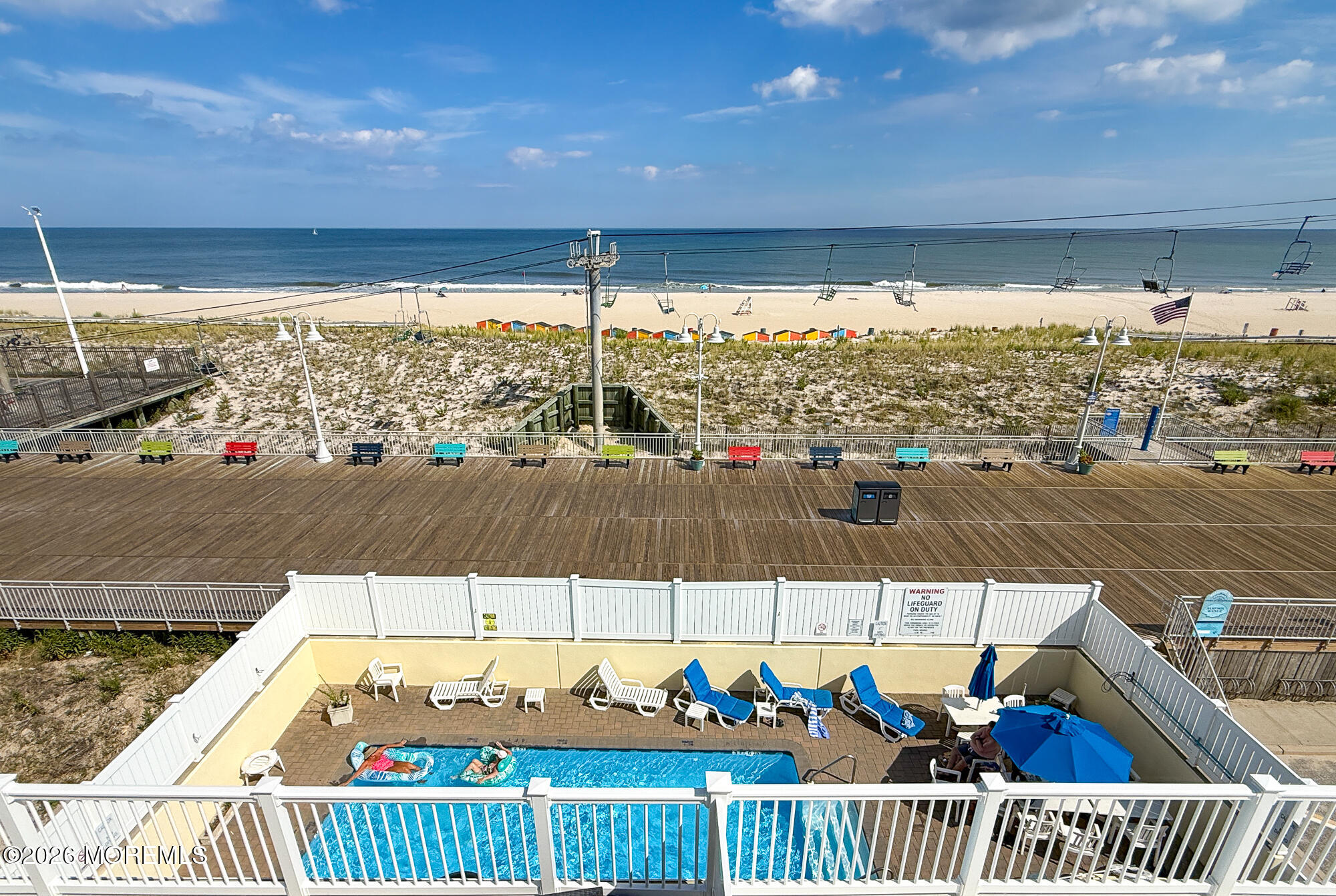 Pool deck overlooking the boardwalk, sandy beach, and ocean.