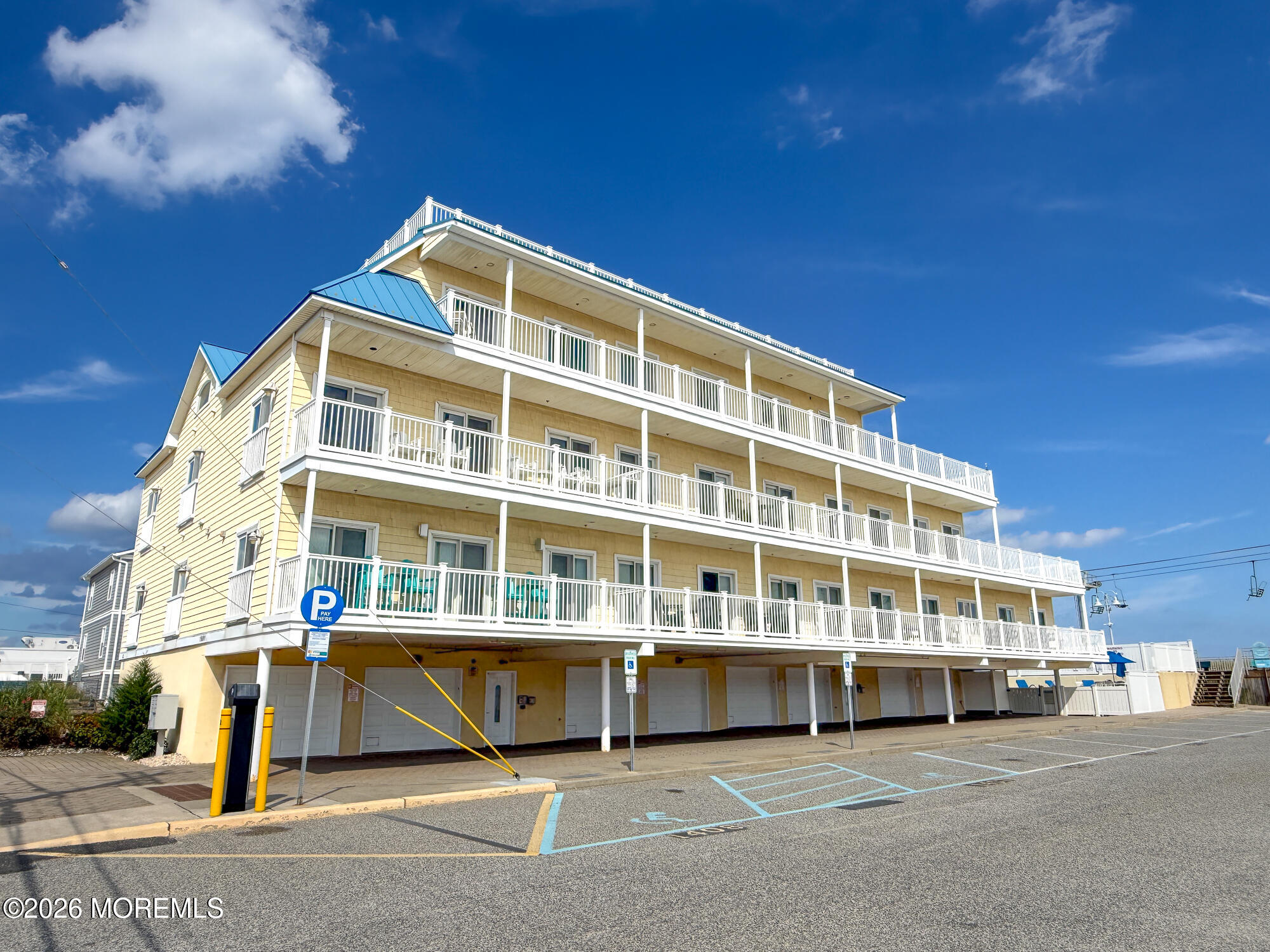 Multi-story yellow building with white-railed balconies and blue roof accents.