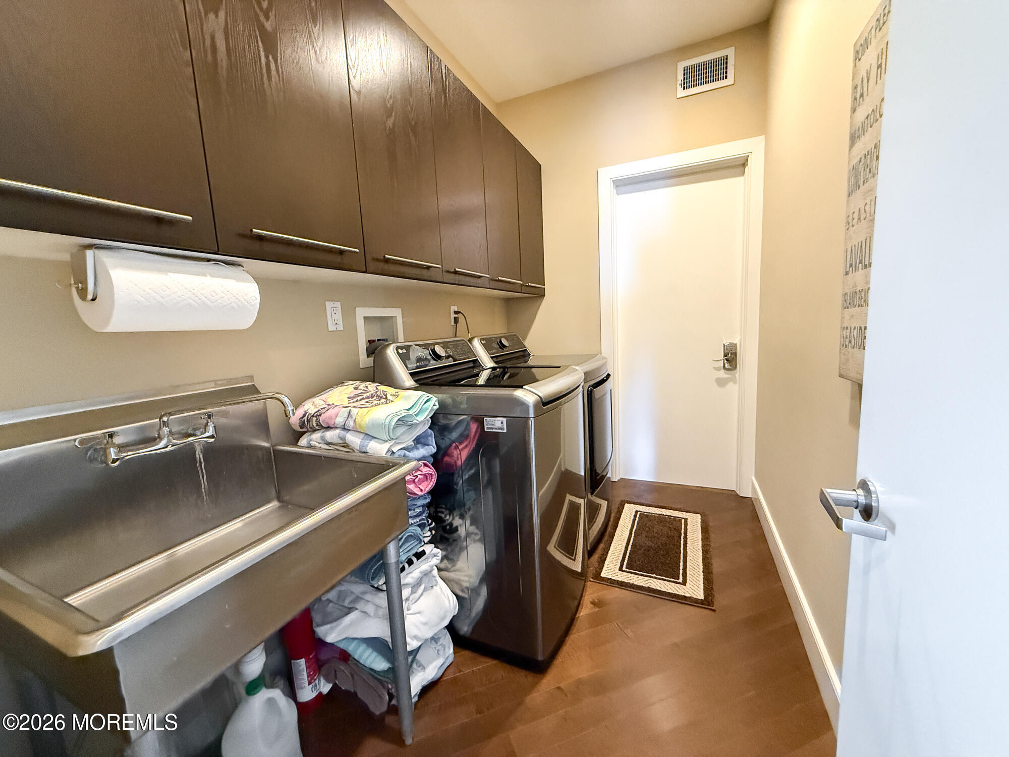 Laundry room with a deep utility sink, washer and dryer, and dark upper cabinets.