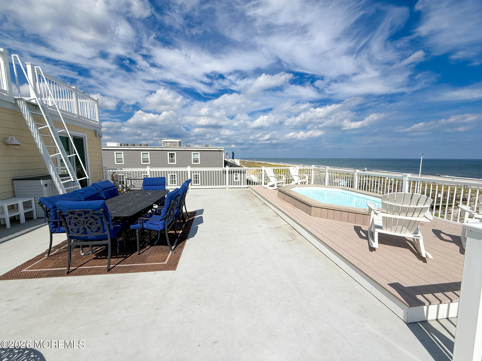 Rooftop deck with blue dining chairs, a small pool, and ocean views.
