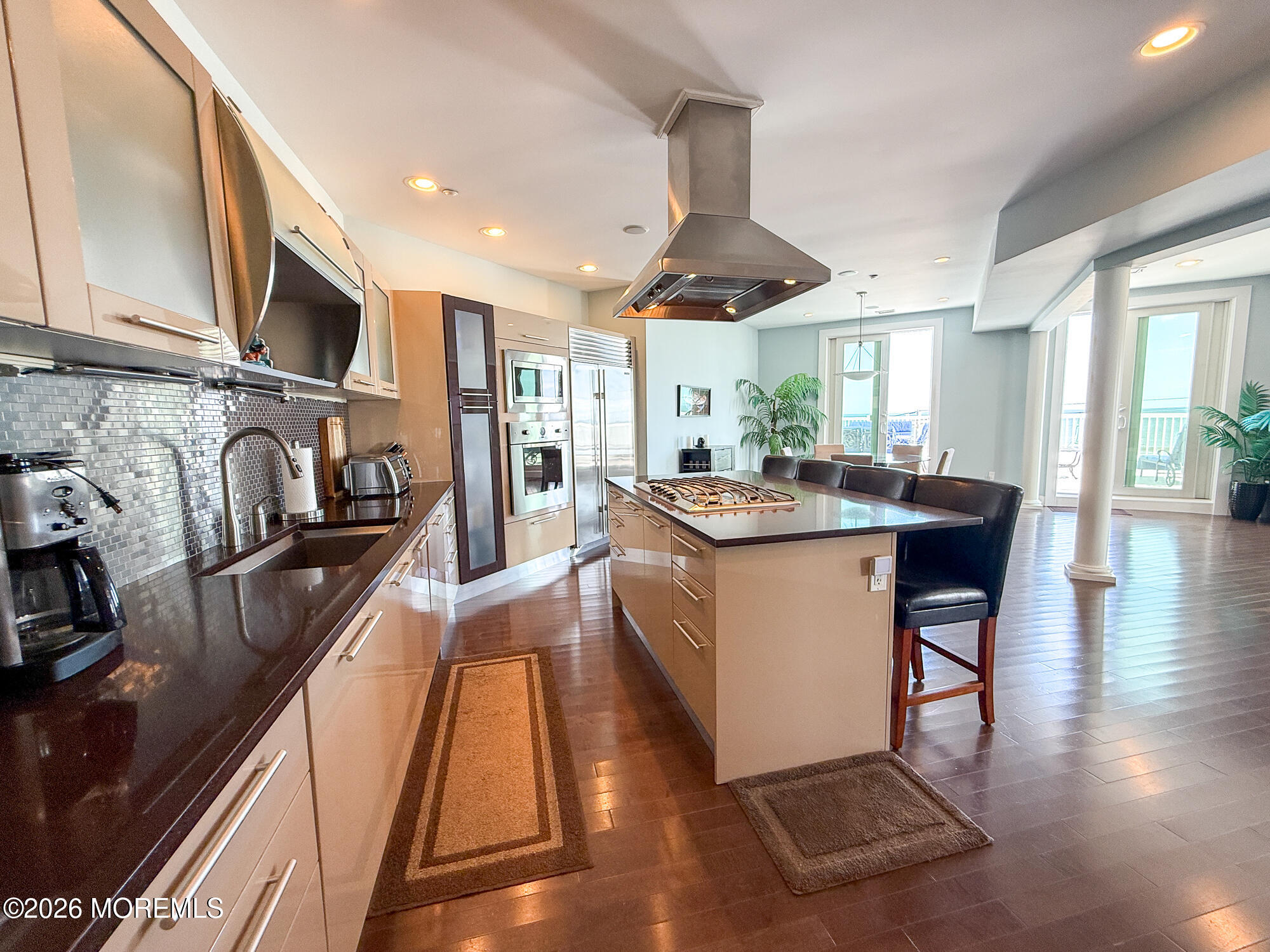 Modern kitchen with a large gas-cooktop island, stainless steel appliances, and balcony doors.