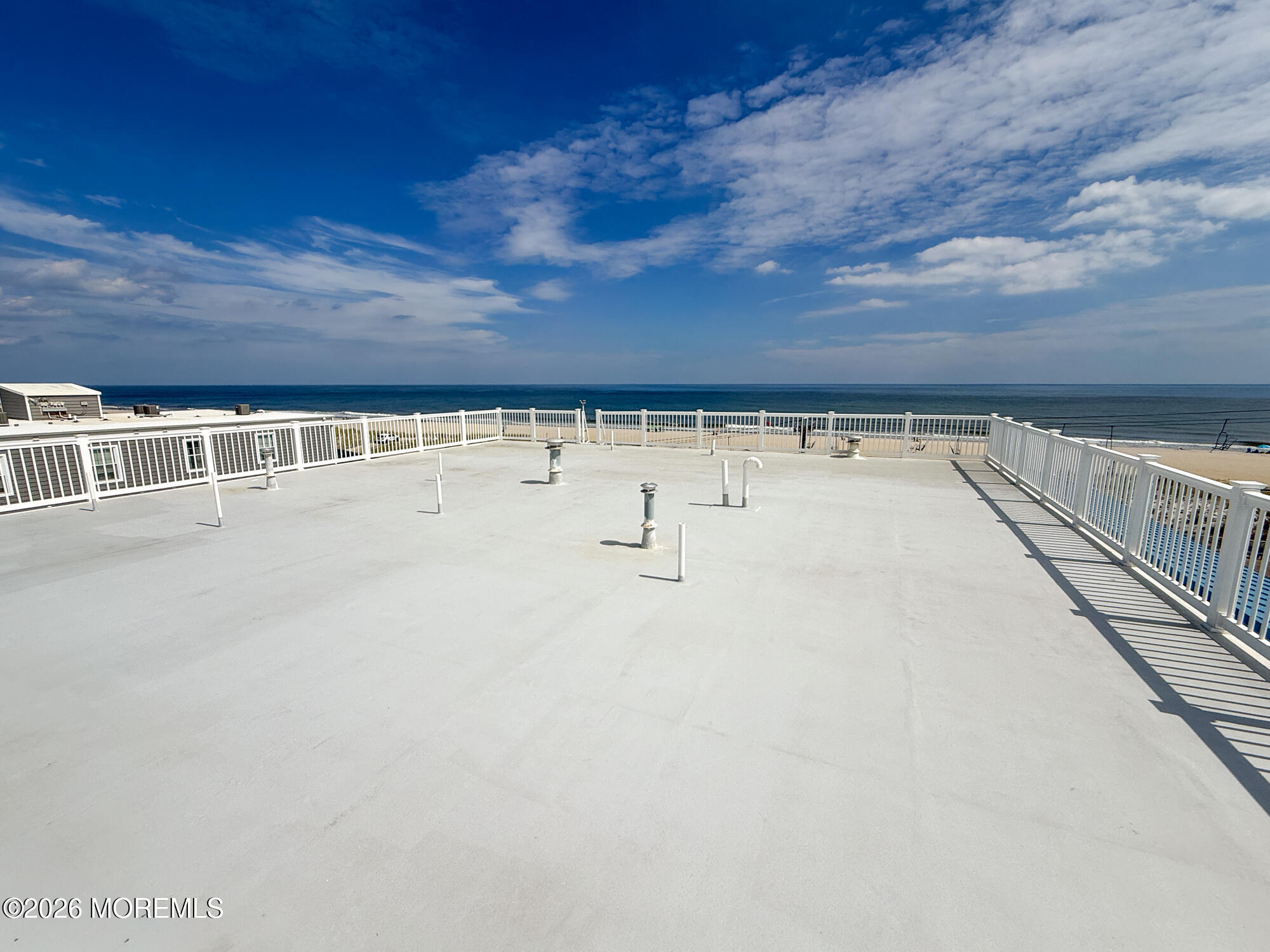 Open rooftop deck with white railings overlooking the ocean.